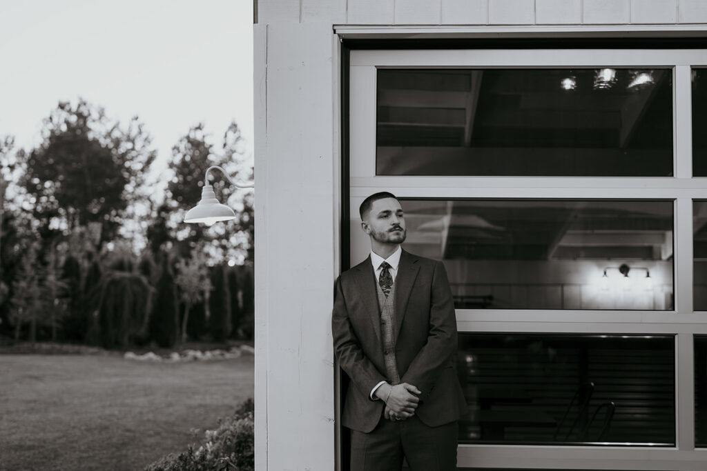 man leaning against wall wearing suit 